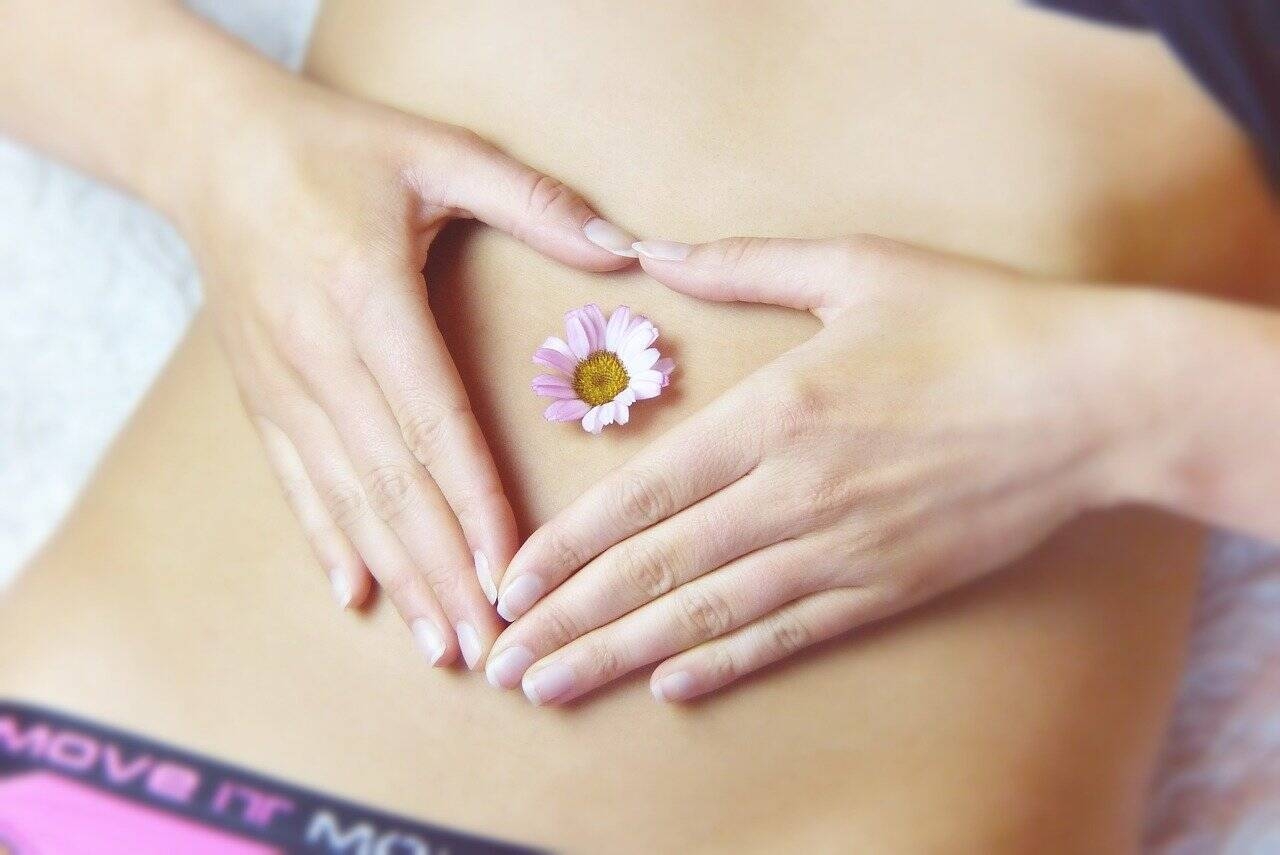 Primo piano su ventre femminile con mani congiunte a formare un cuore 